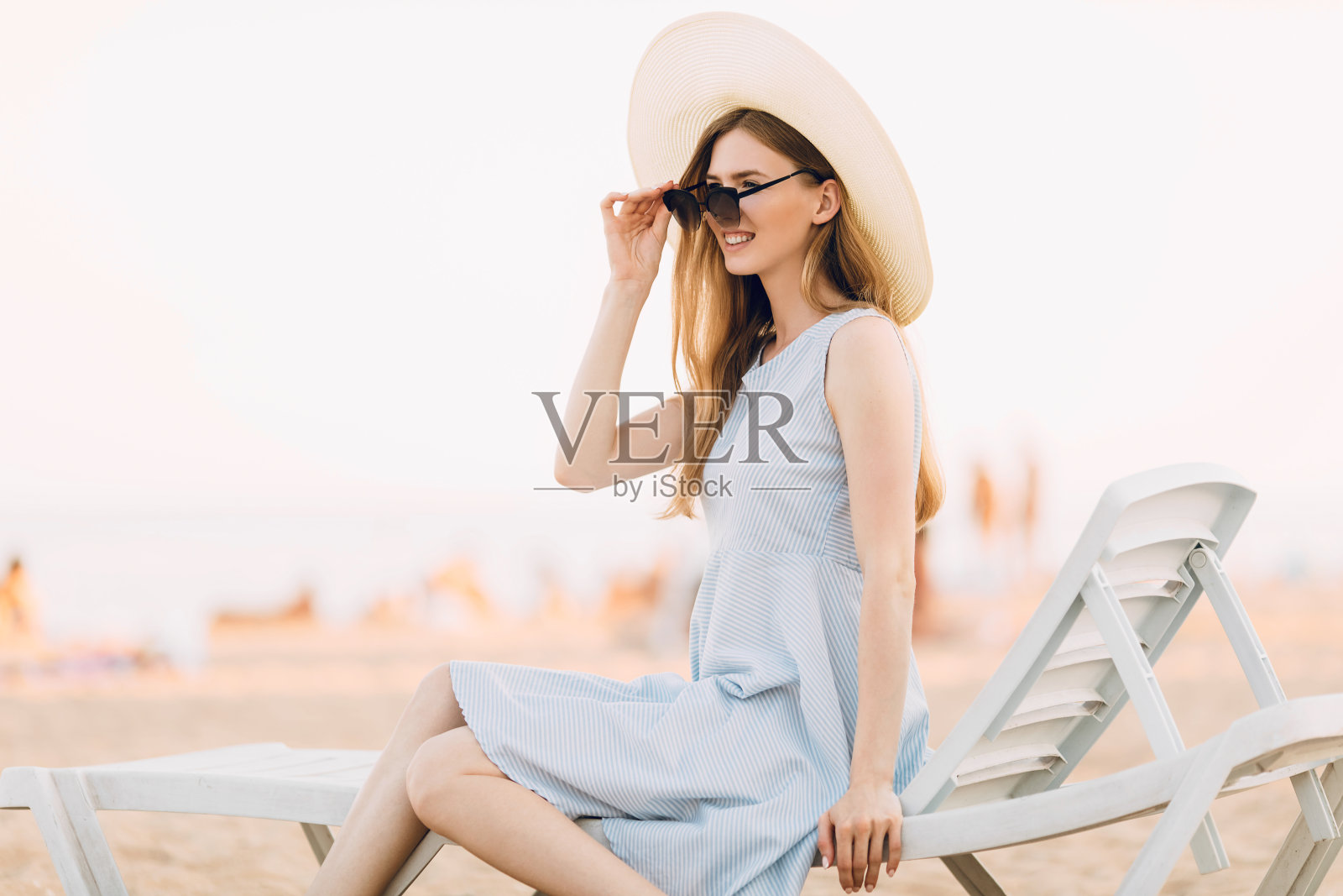 快乐放松迷人的女孩戴着太阳镜和夏天的帽子，放松在海上，坐在躺椅上。暑假，旅游，出海照片摄影图片