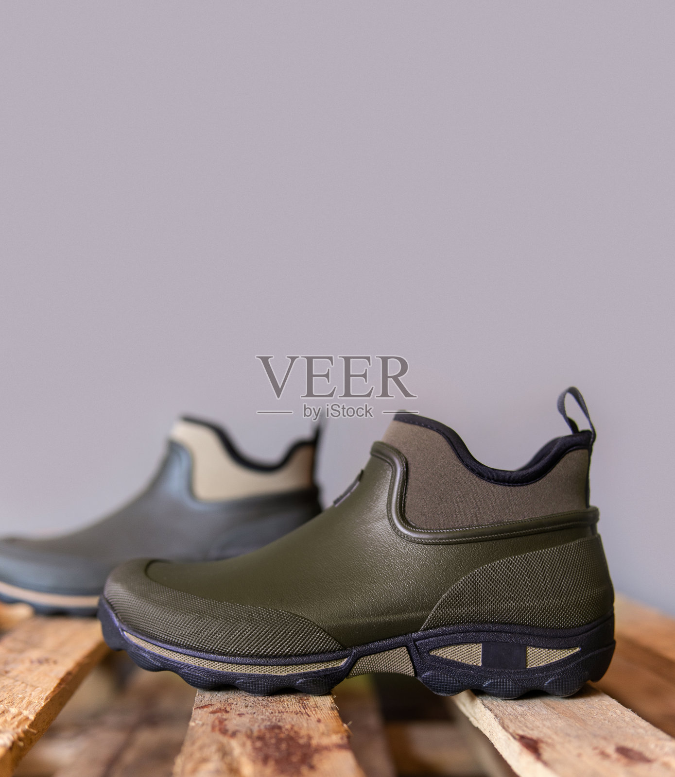 橡胶靴在木板上。适合恶劣天气或园艺的鞋子。农民、猎人或园丁的鞋子。照片摄影图片