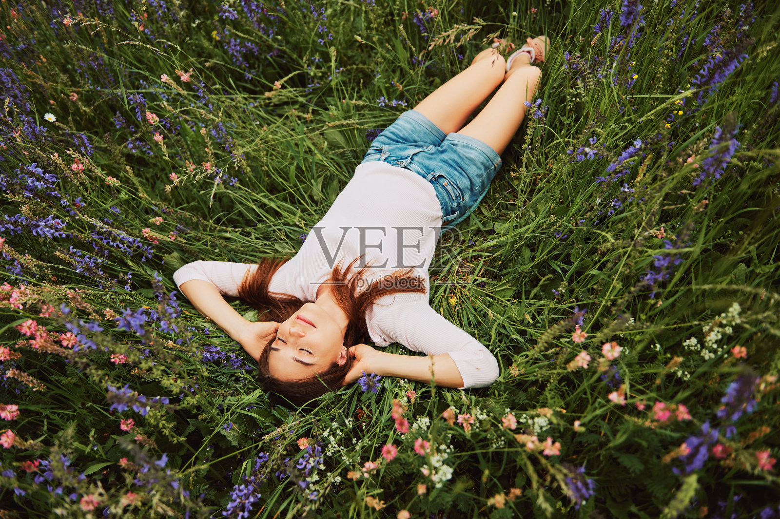 年轻女子躺在田野里，享受美好的一天，与大自然融为一体照片摄影图片