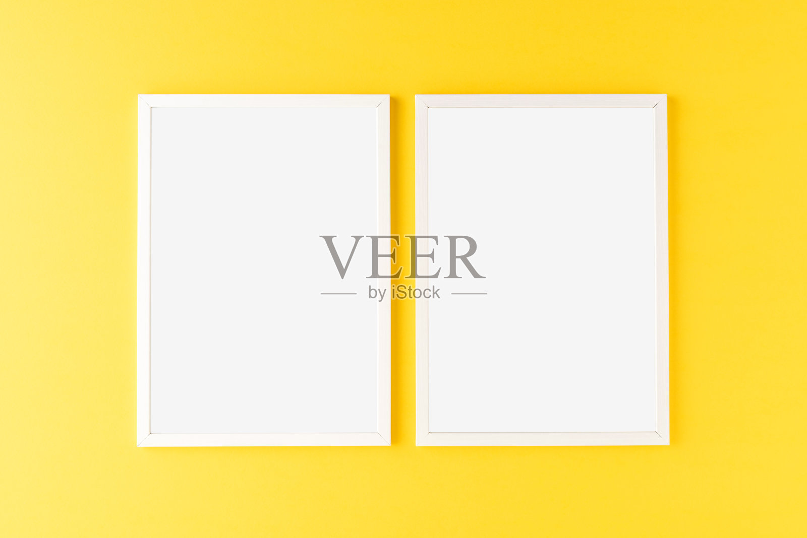 两个空的相框挂在黄色的墙上。模型照片摄影图片