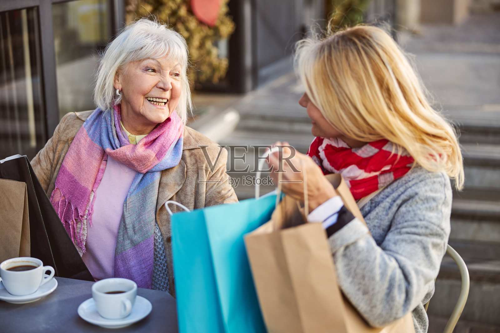 快乐友好的女士们互相展示购物袋里的新衣服照片摄影图片
