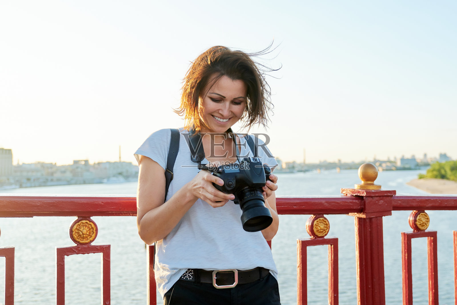 成熟的女性摄影师，专业的相机和背包照片摄影图片