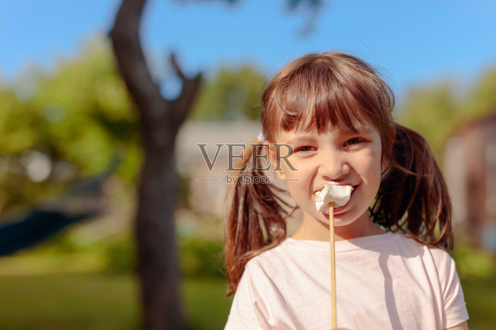 一个四岁的小女孩在吃烤棉花糖。照片摄影图片