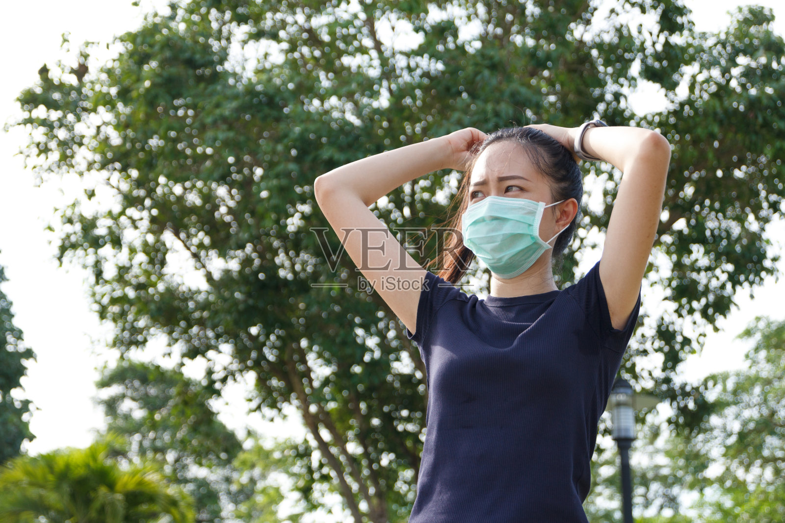 年轻的亚洲妇女在医疗防护口罩做伸展热身晨练前。户外工作。健康的概念照片摄影图片