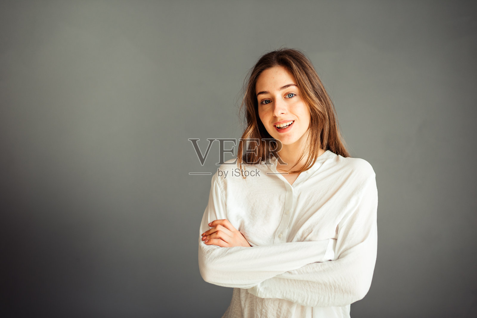 穿着白衬衫的年轻女孩，举起手，在灰色的背景上。诚实和情感上的横幅，广告牌，广告牌。没有修整。没有化妆。照片摄影图片