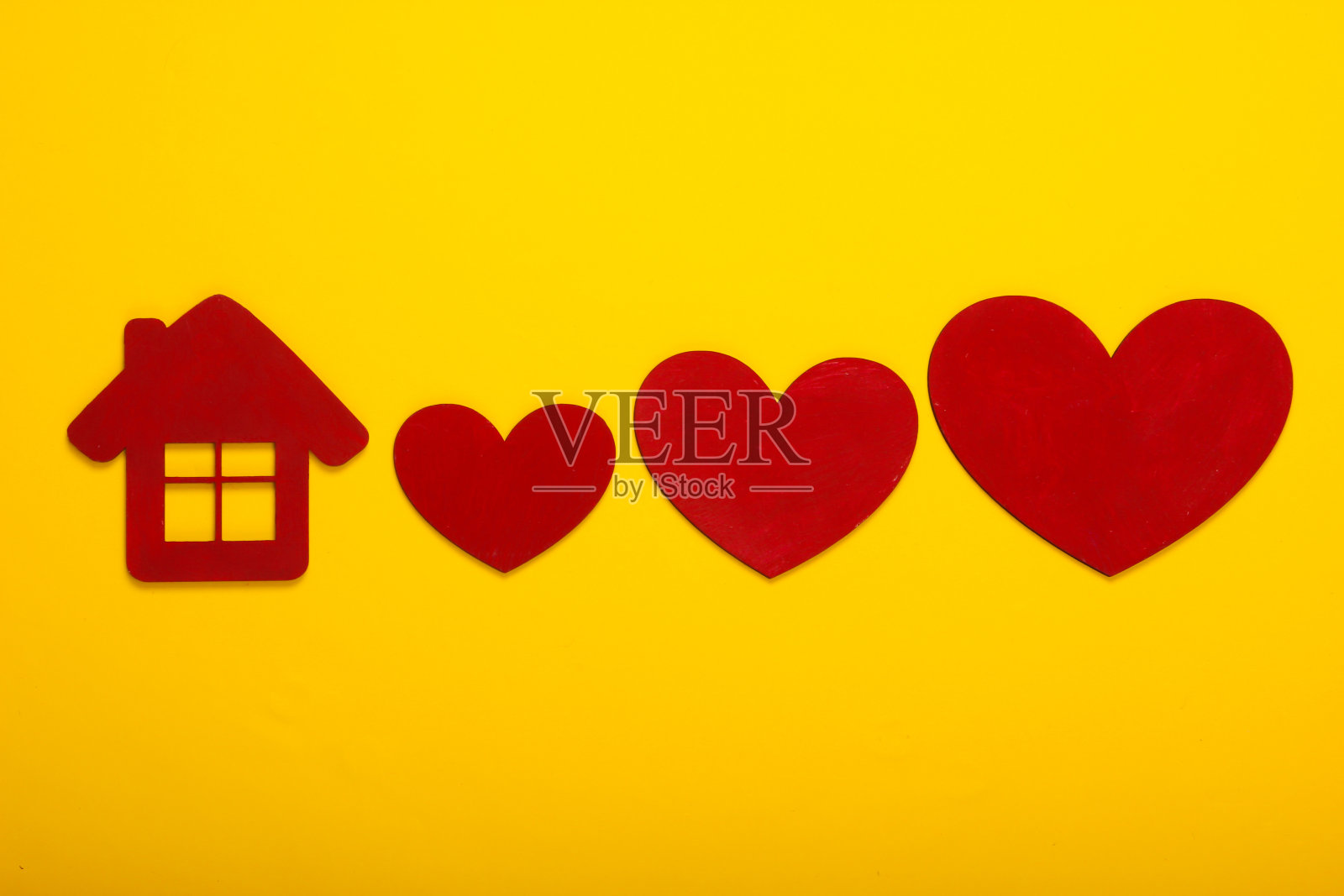 红色的木心和黄色背景上的房子小雕像照片摄影图片