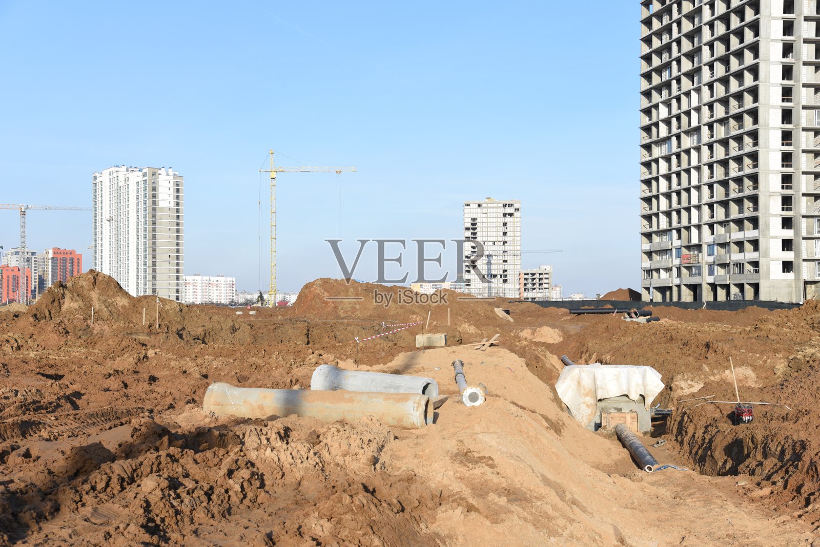 塔吊正在建造一座新的住宅楼。铺设或更换地下雨水下水道。照片摄影图片