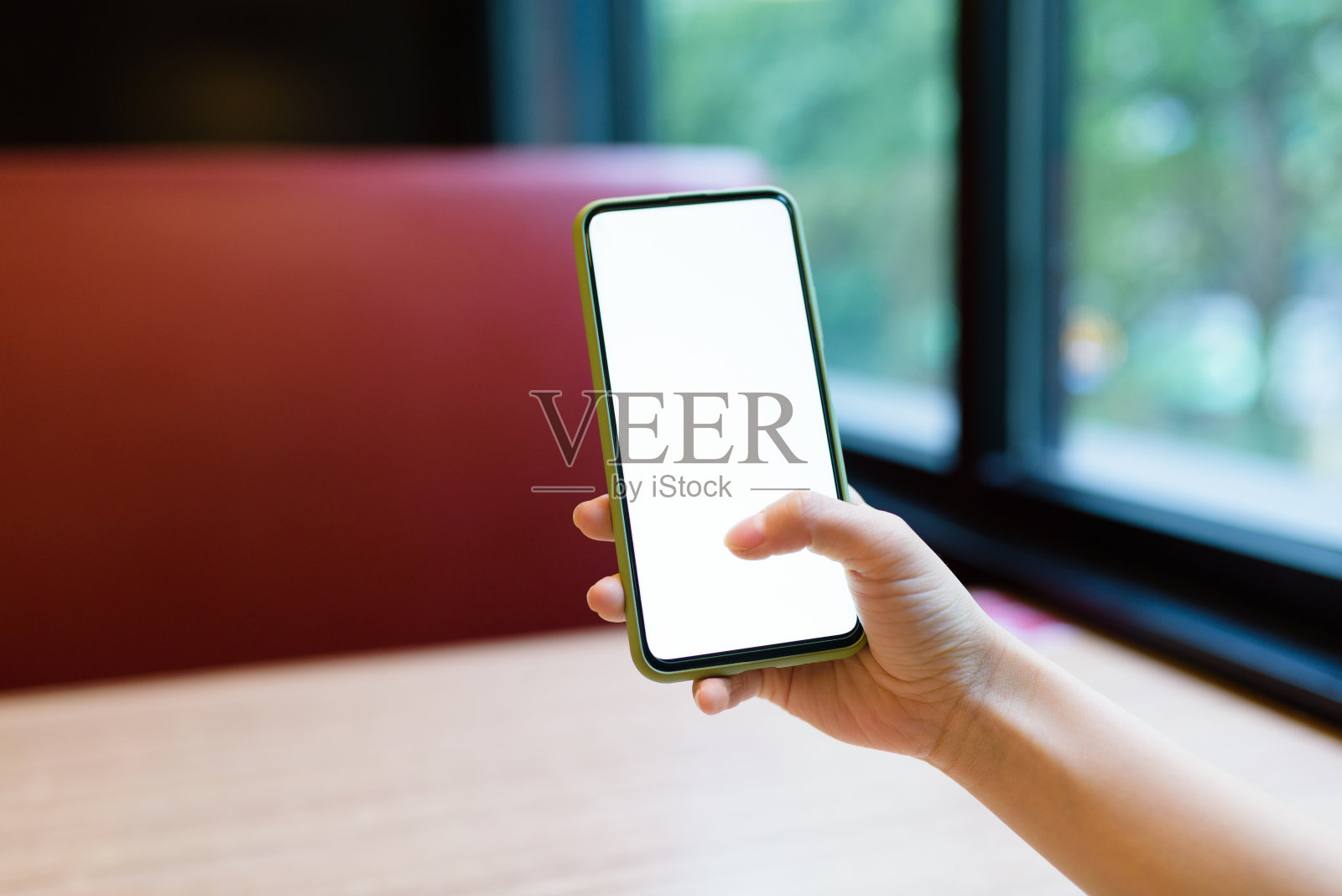 在咖啡馆里用智能手机剪女人的手。照片摄影图片