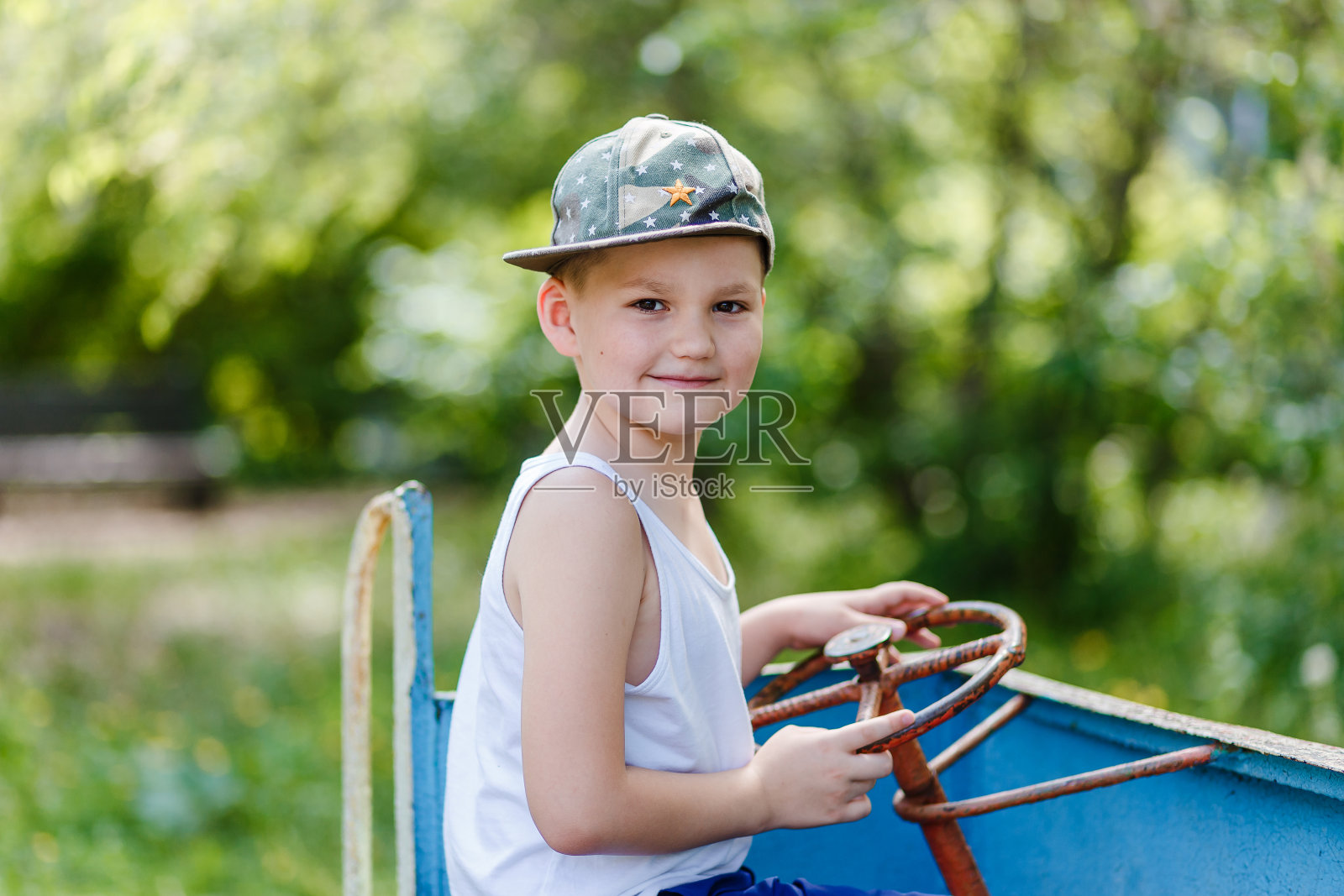 孩子坐在儿童车里，在操场上握着方向盘照片摄影图片