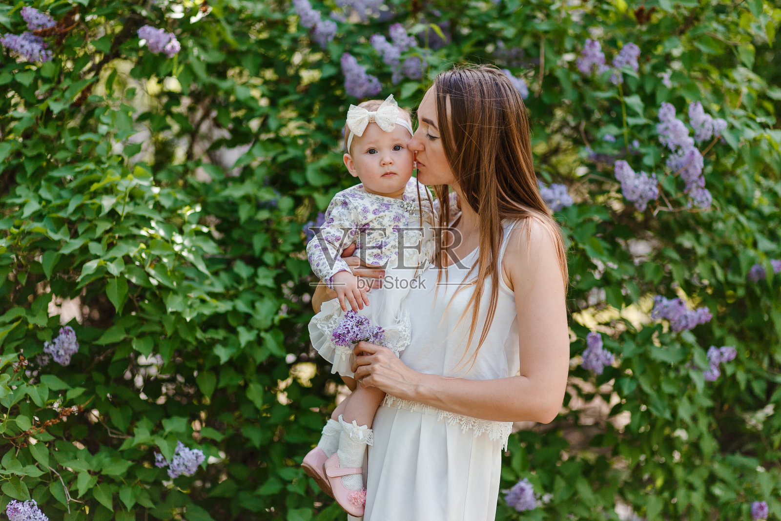 年轻美丽的女人亲吻小女孩的脸颊在夏天照片摄影图片