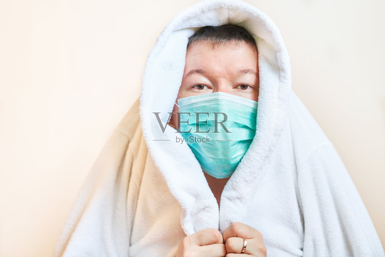 一个戴着医用口罩的男人用家居服遮住自己，自我隔离，隔离，呆在家里，恐惧照片摄影图片