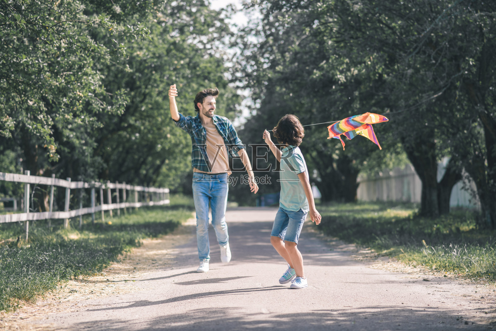 黑头发的男孩和他的父亲在追五颜六色的风筝看起来很开心照片摄影图片