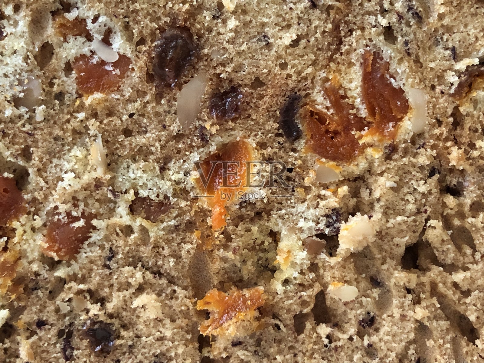 这是一个新鲜的蛋糕，上面有坚果、葡萄干和杏干，撒上糖粉，整块或整块的照片摄影图片