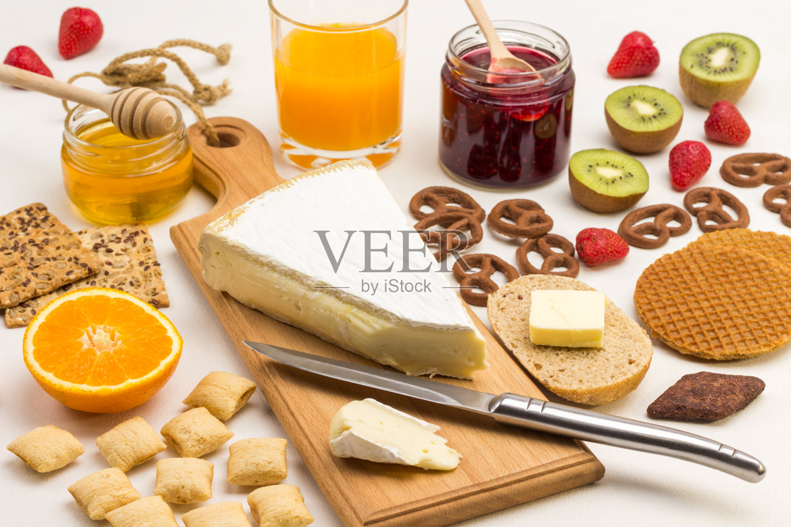平衡的蛋白质的早餐。布里奶酪放在砧板上。饼干，水果和浆果，橙汁照片摄影图片