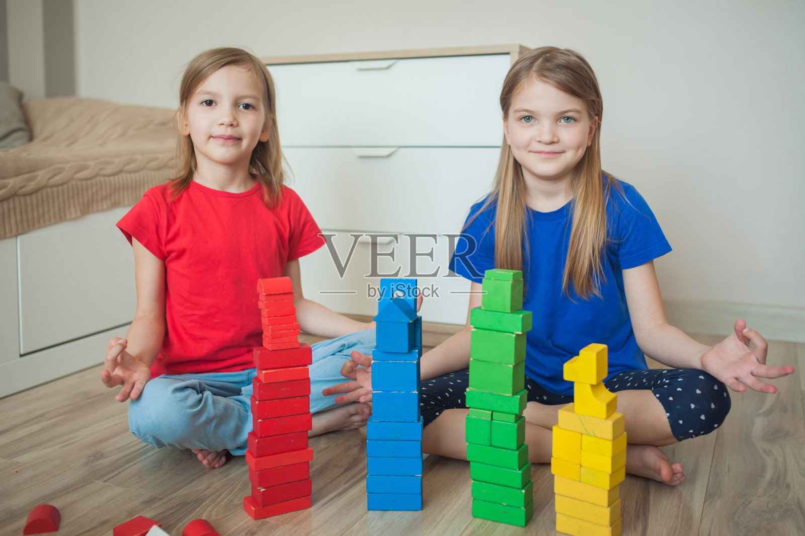 两个姐妹在孩子的房间里搭起了塔，坐成莲花状。照片摄影图片