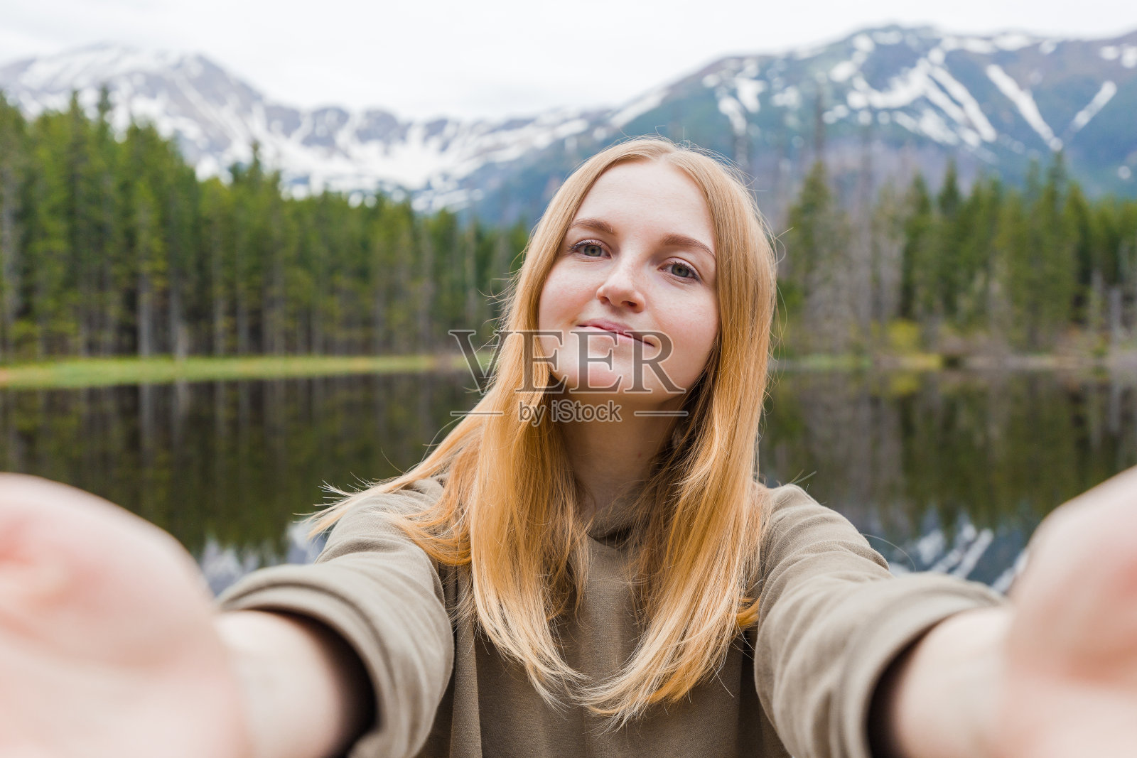女游客在山上的湖里自拍。看着镜头微笑。旅行和积极的生活理念。在户外照片摄影图片