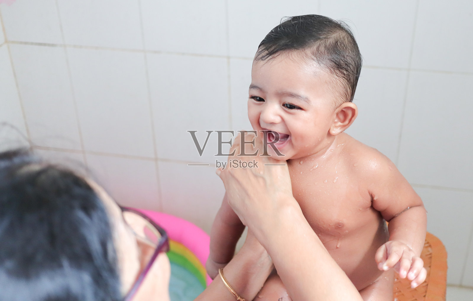 一个可爱的印度无辜的新生儿在愉快的心情与迷人的微笑与水滴在他的身体在淋浴。照片摄影图片