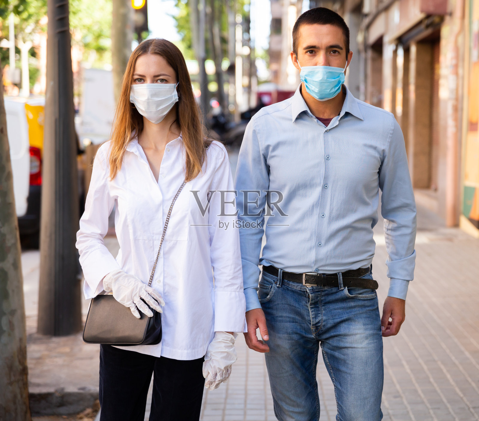 戴着医用口罩的夫妇走在城市街道上照片摄影图片