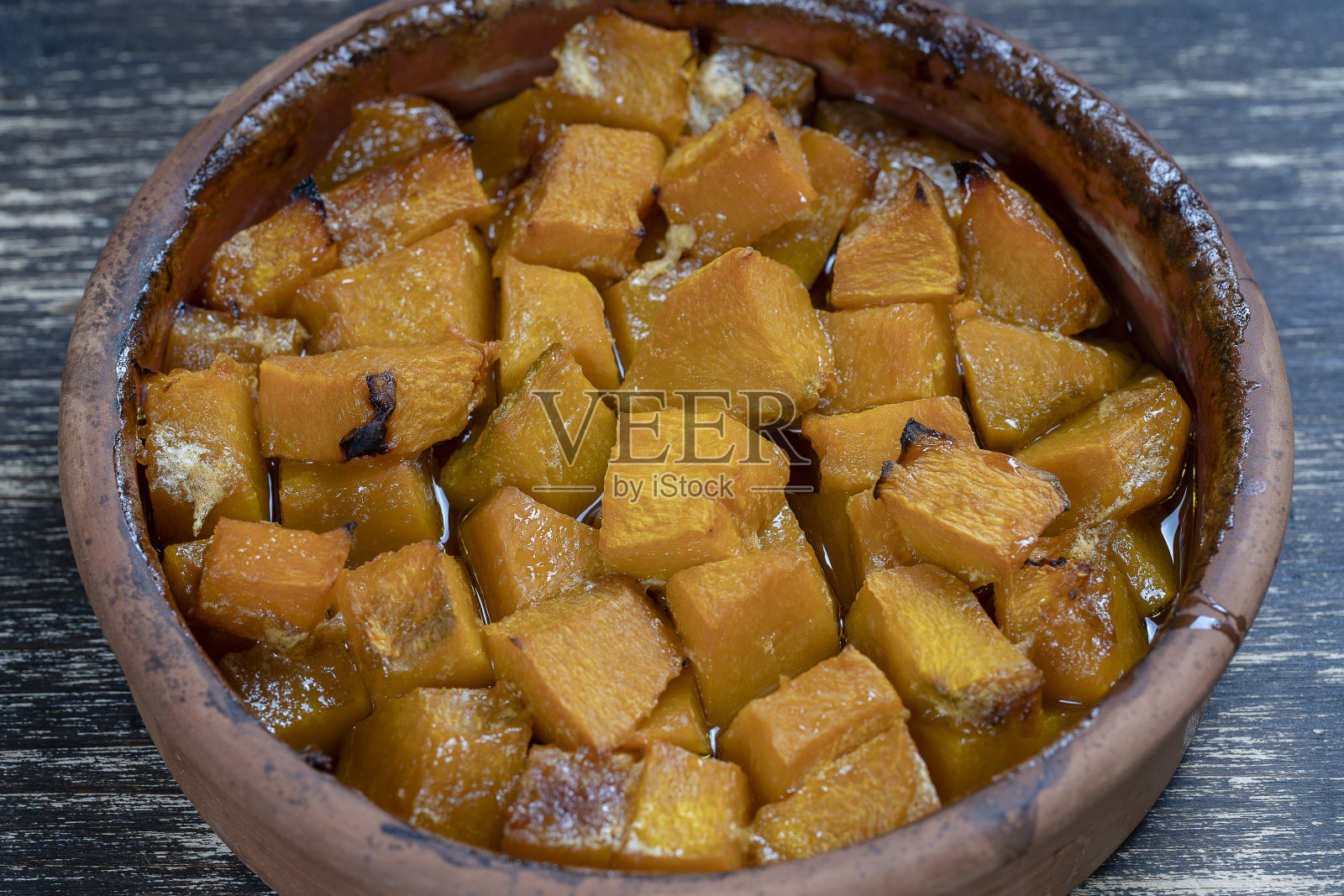 木桌上放着烤好的黄色南瓜，配上蜂蜜、橄榄油和香料。素食。特写镜头照片摄影图片