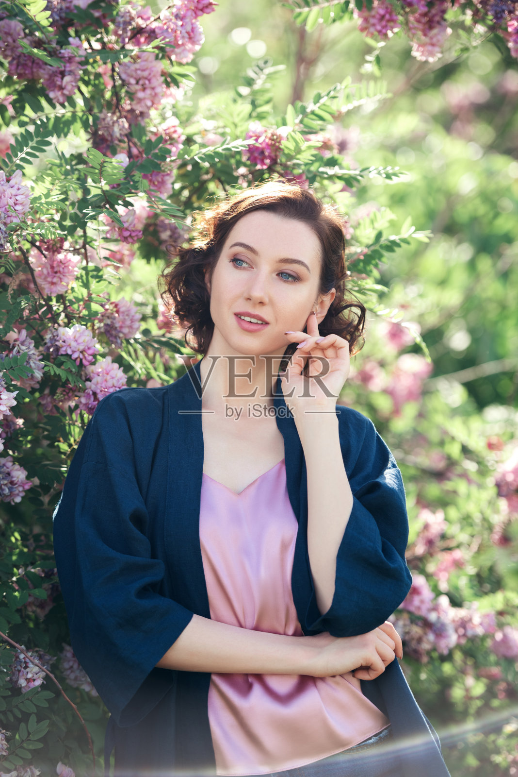 年轻美丽的梦幻女孩在盛开的相思的背景。照片摄影图片