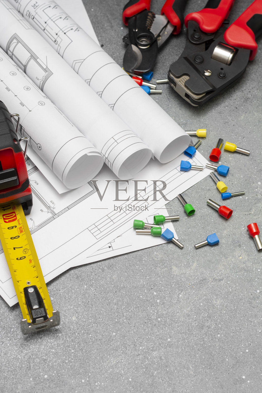 用于压接绞合电线的不同尺寸和颜色的工具和尖端。灰色混凝土背景上的压线工具、导线头和电缆照片摄影图片