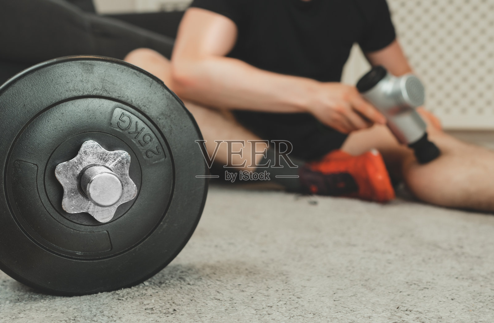 男人按摩腿用按摩叩击器。照片摄影图片