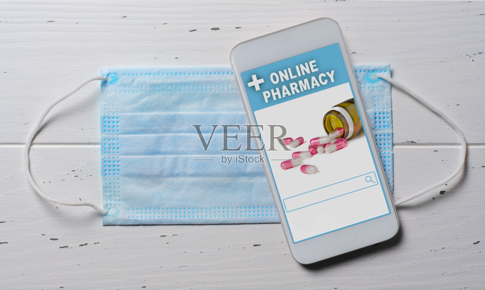 网上药店。在智能手机上的应用，在线订购药品。医用一次性口罩和白色背景的手机。方便选择药物的概念照片摄影图片