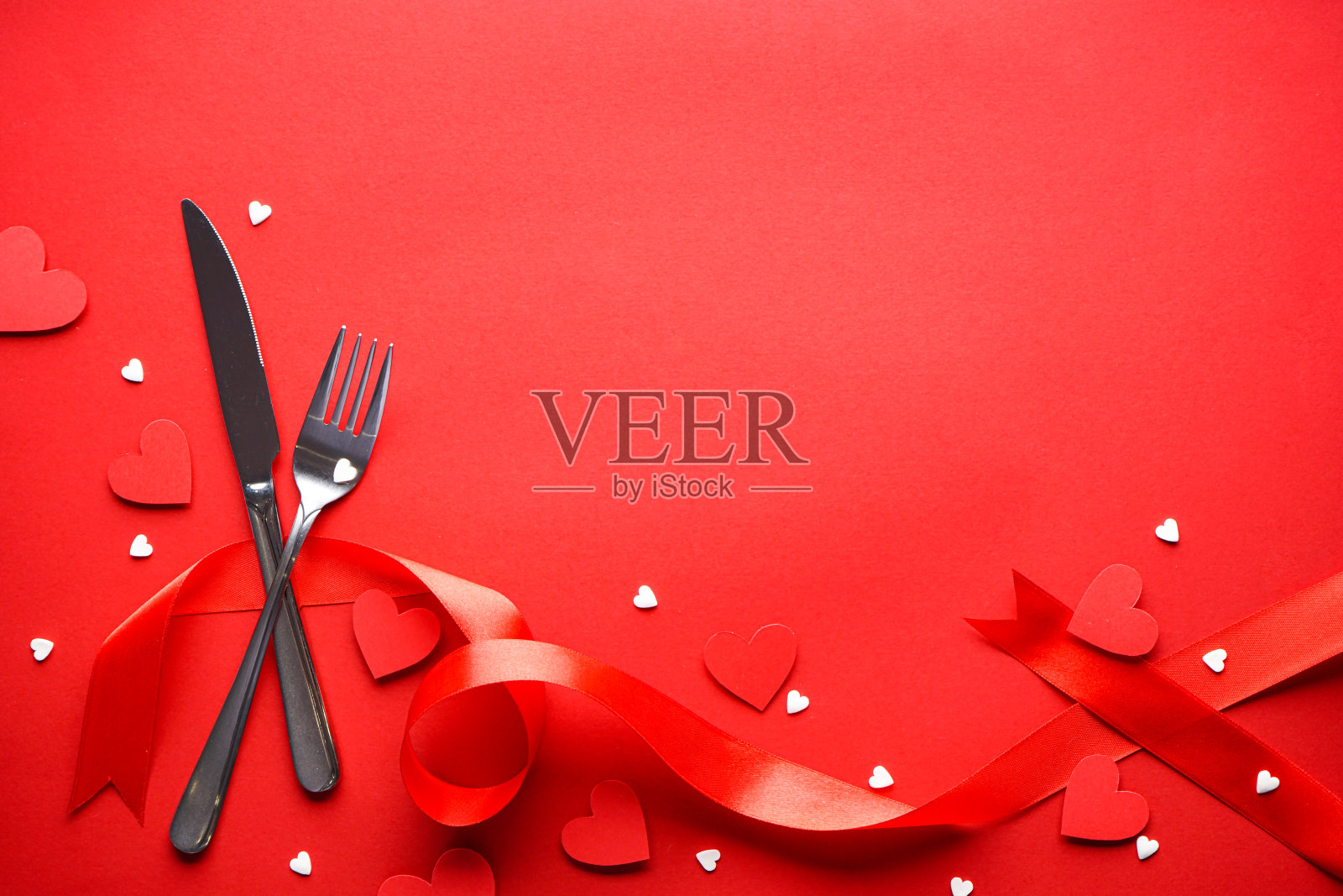 心形餐具和红丝带在红色的背景，有文字的空间。情人节。爱的概念。母亲的一天。照片摄影图片