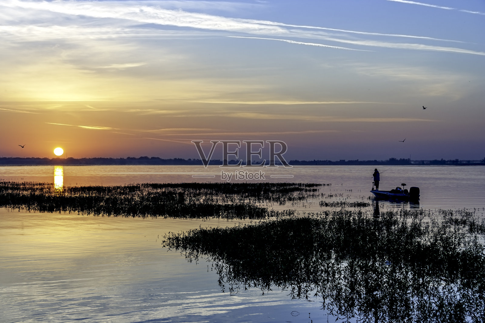 在托霍普卡利加湖——一个全国著名的巴斯钓鱼湖——上，太阳升起在这个孤独的渔夫的渔船上照片摄影图片