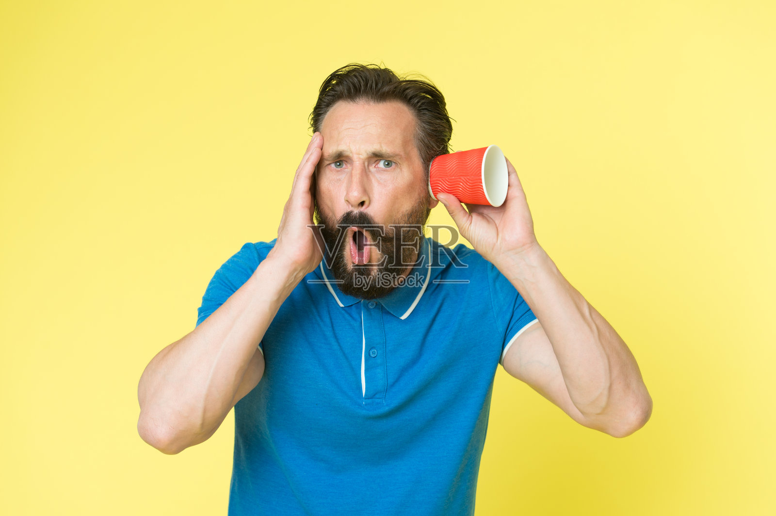 耳朵和听力保健。成熟的男人会耳聋或听力丧失。听力障碍。听力测试。大胡子男人隔着玻璃听。特务或间谍。间谍和偷听照片摄影图片