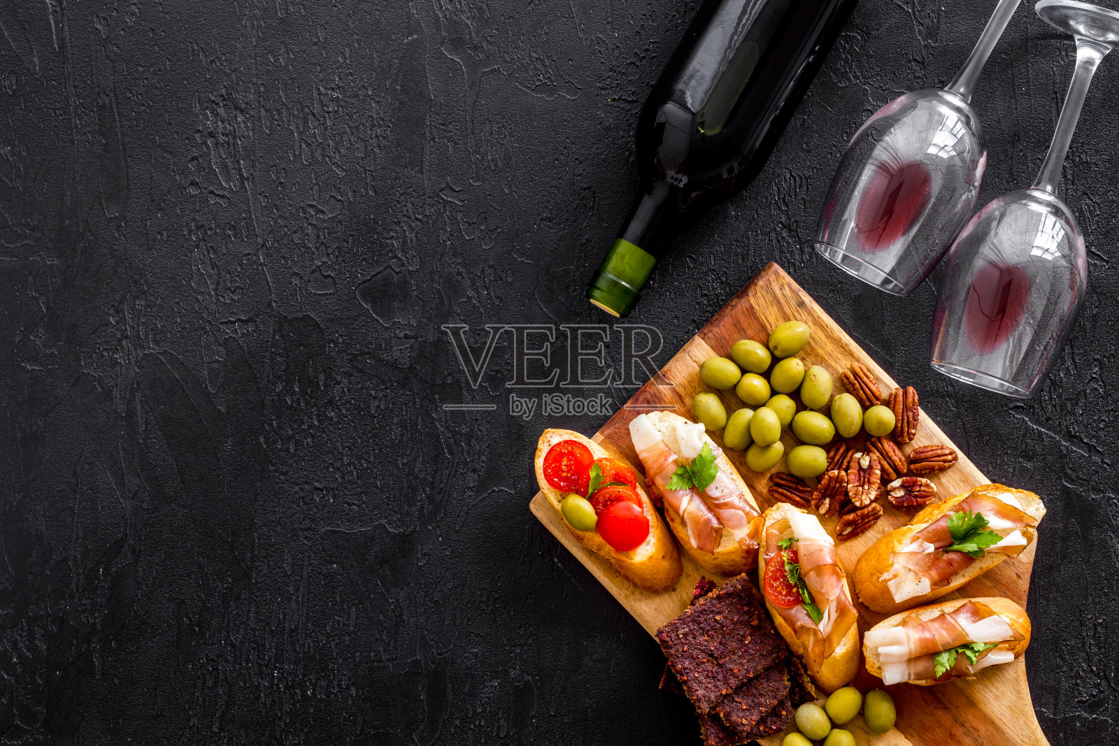 酒开胃菜。烤面包，坚果，橄榄放在黑色的桌子上照片摄影图片