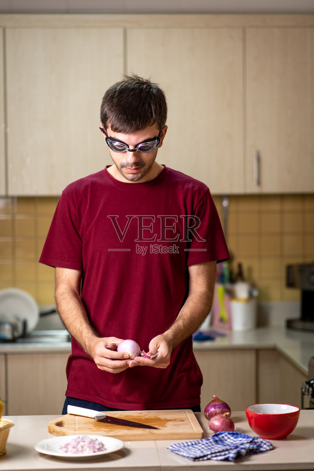 戴着游泳镜在厨房切洋葱的男人照片摄影图片