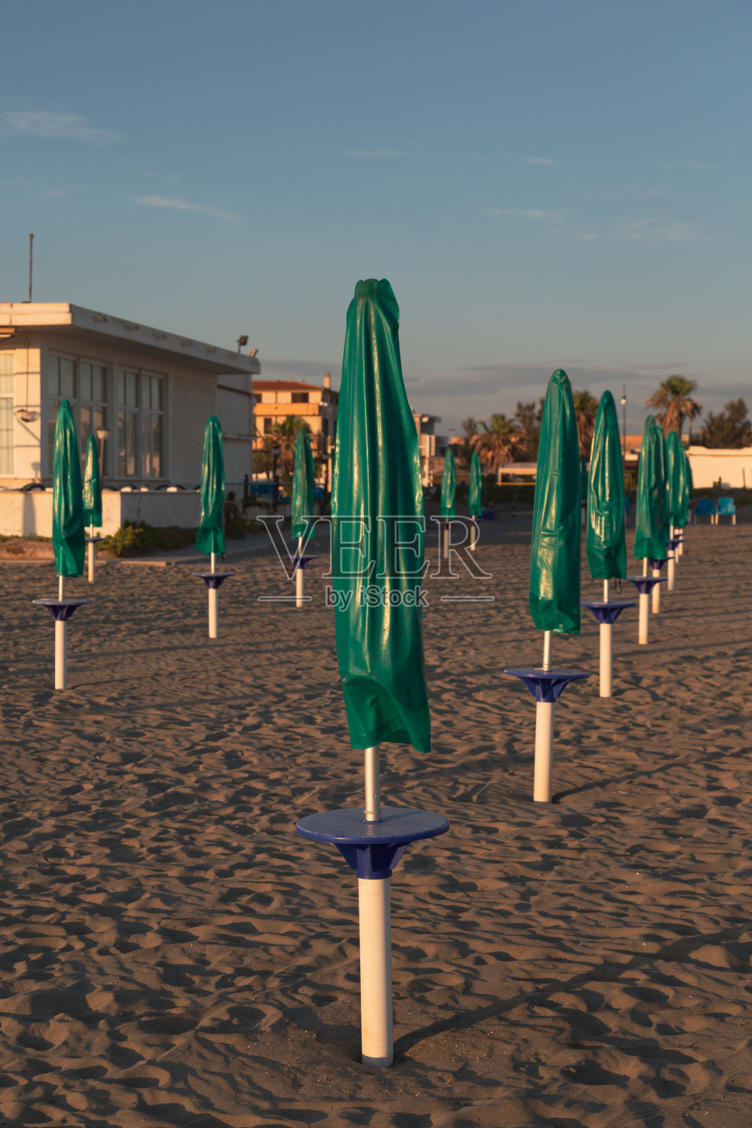 意大利拉齐奥罗马菲乌米契诺海滩上的绿色遮阳伞。照片摄影图片