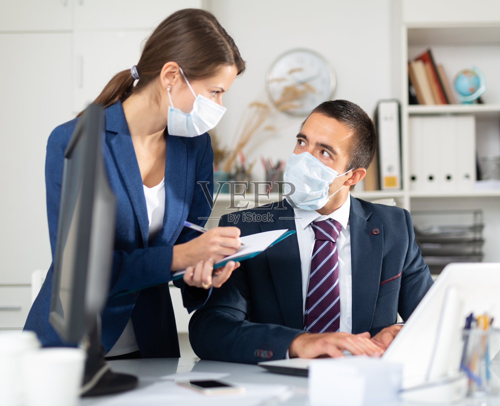 商人和女同事带着医用口罩在办公室工作照片摄影图片