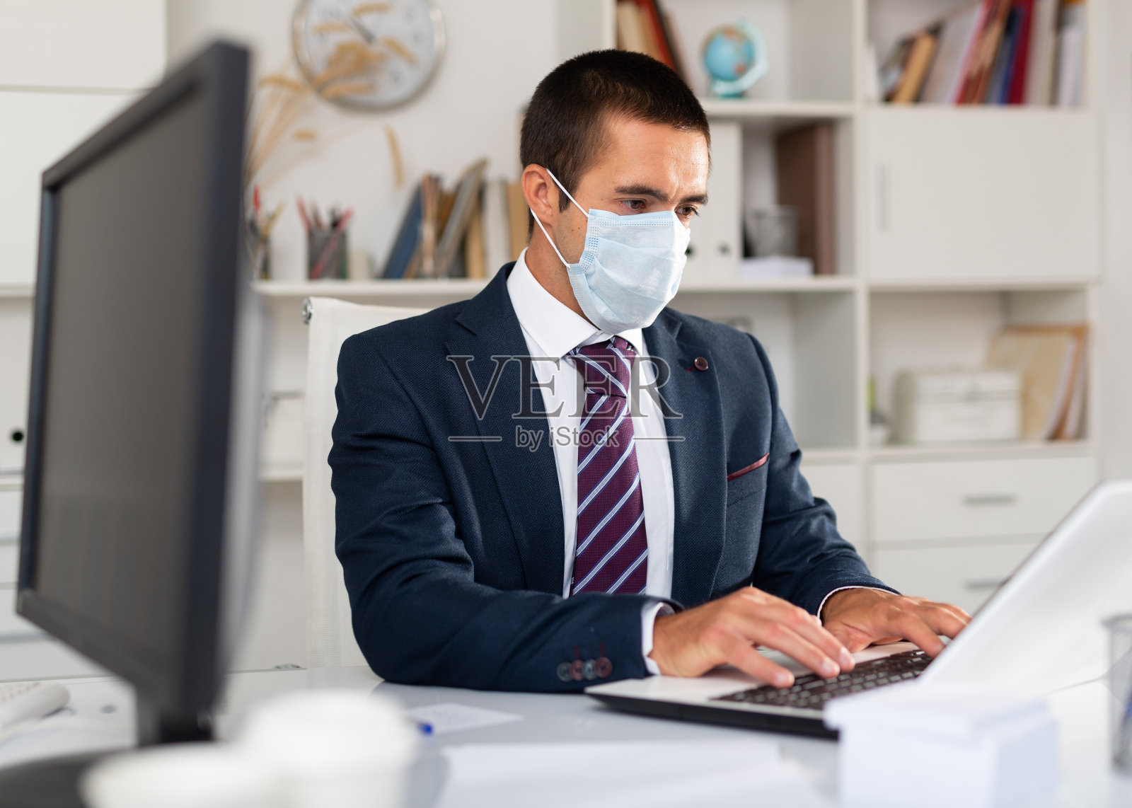 专注于戴口罩的商人在办公室工作照片摄影图片
