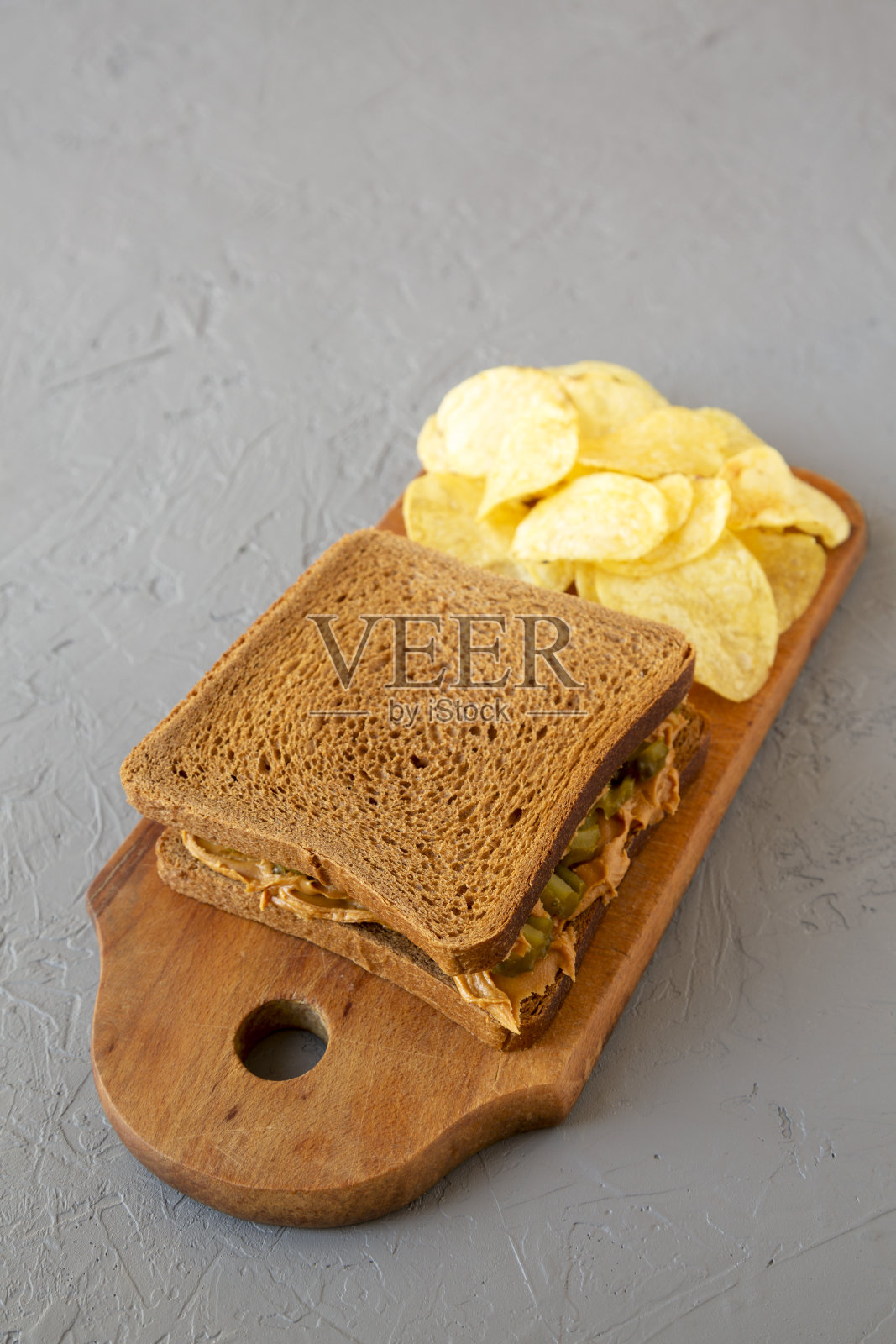 自制花生酱泡菜三明治和薯片在一个乡村木板上灰色的背景，低角度的观点。副本的空间。照片摄影图片