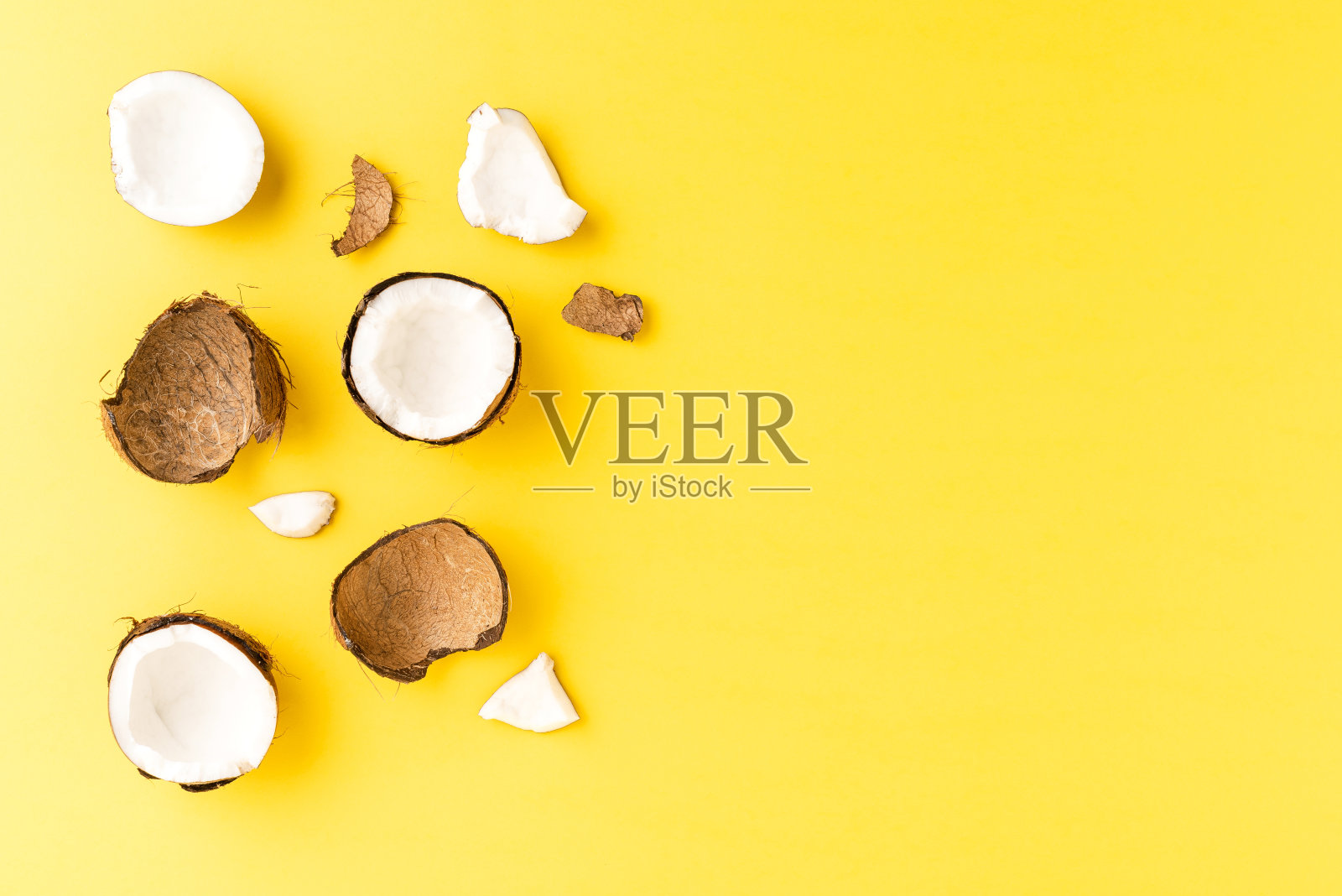 破碎的椰子在黄色背景与copyspace。俯视图照片摄影图片