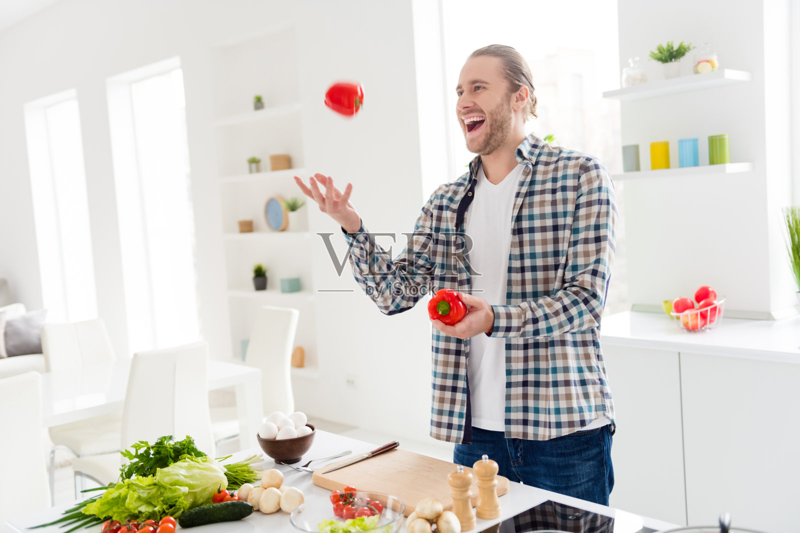 他的肖像，他很好，有吸引力，愉快，愉快的家伙做有用的减肥，家庭菜午餐玩番茄烹饪，在现代的浅白色室内风格厨房室内的乐趣照片摄影图片
