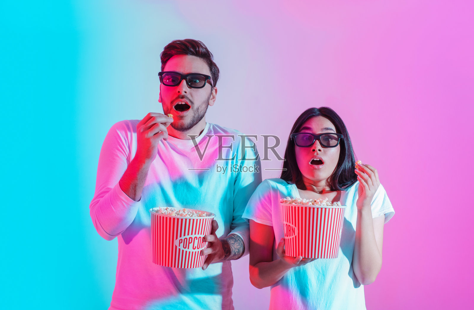 电影中的特效。一对戴着3D眼镜的惊讶男孩和女孩正捧着爆米花照片摄影图片