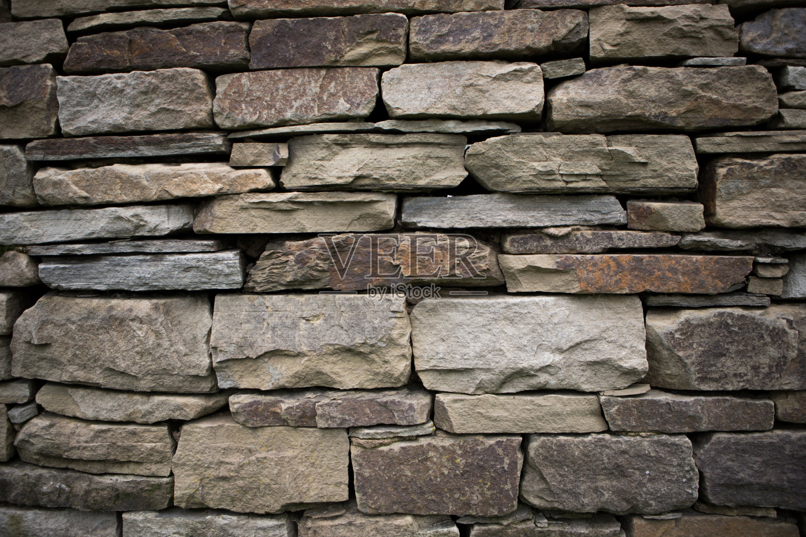 用不同大小的石头手工建造的干石墙。细节和纹理。照片摄影图片