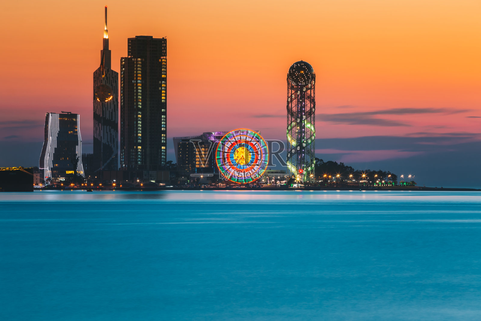 巴统,Adjara,格鲁吉亚。日落日出时度假小镇的天际线。明亮的橙色夜空。从海上看，以现代城市建筑、摩天大楼和塔楼照亮城市景观。金色的小时照片摄影图片