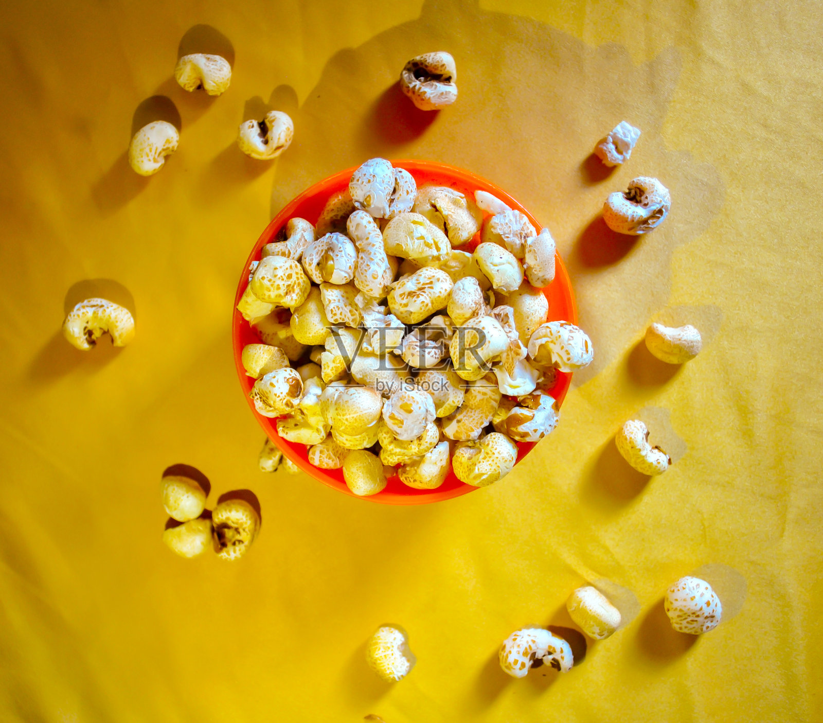 黄色背景的橙色碗里的爆米花照片摄影图片