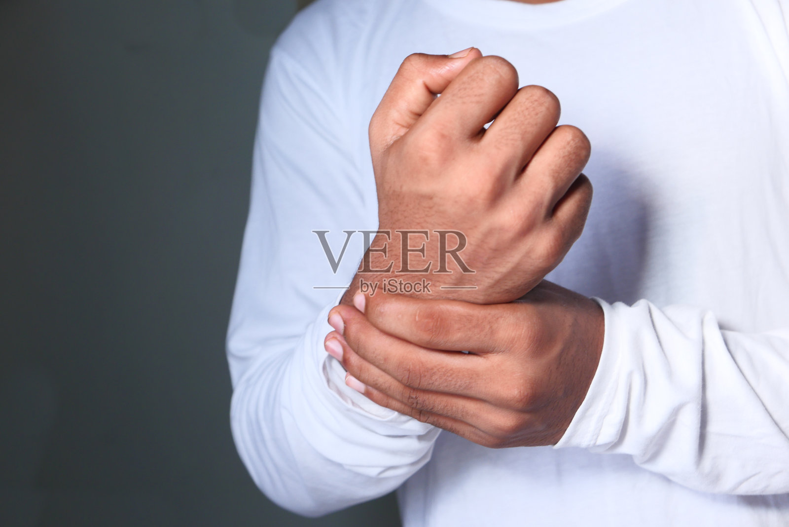 年轻人在忍受着手腕的疼痛，近处照片摄影图片