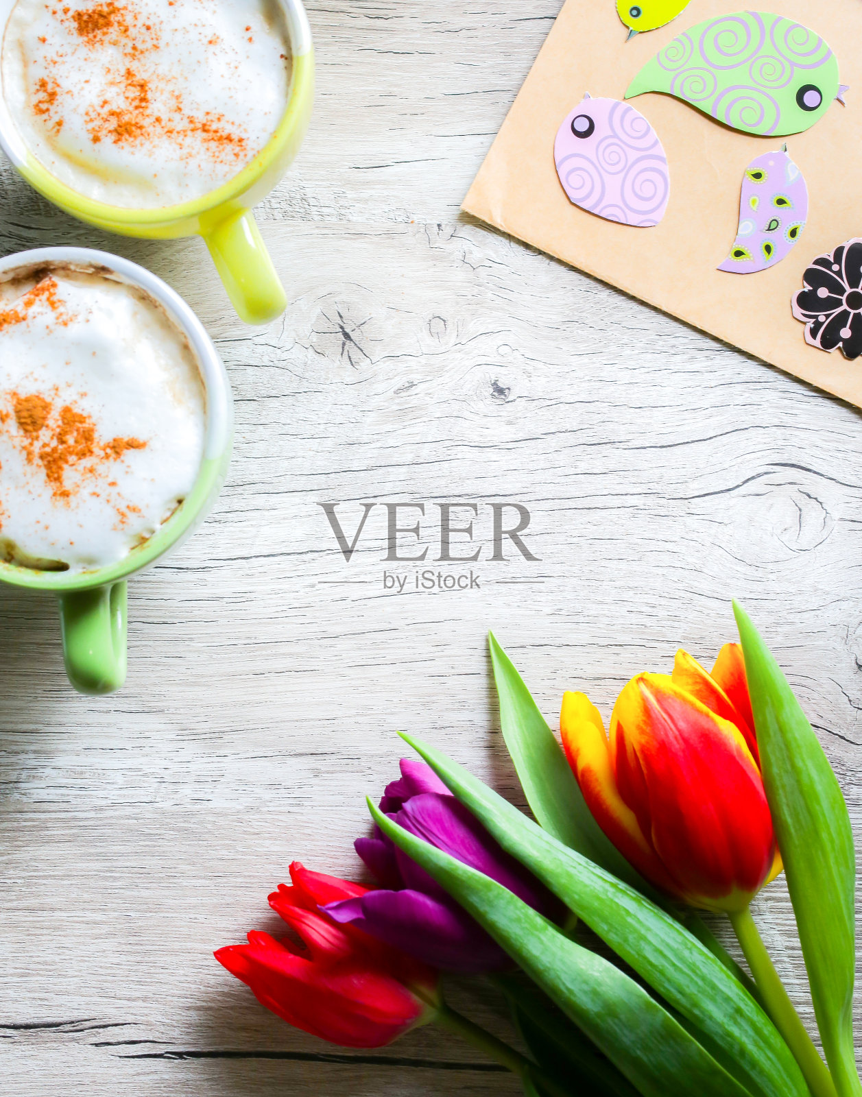 木雕郁金香，两杯咖啡。邀请明信片母亲节或国际妇女节。春天百花盛开，鸟语缤纷。手工折纸。强力的彩笔。卡布奇诺与肉桂。照片摄影图片