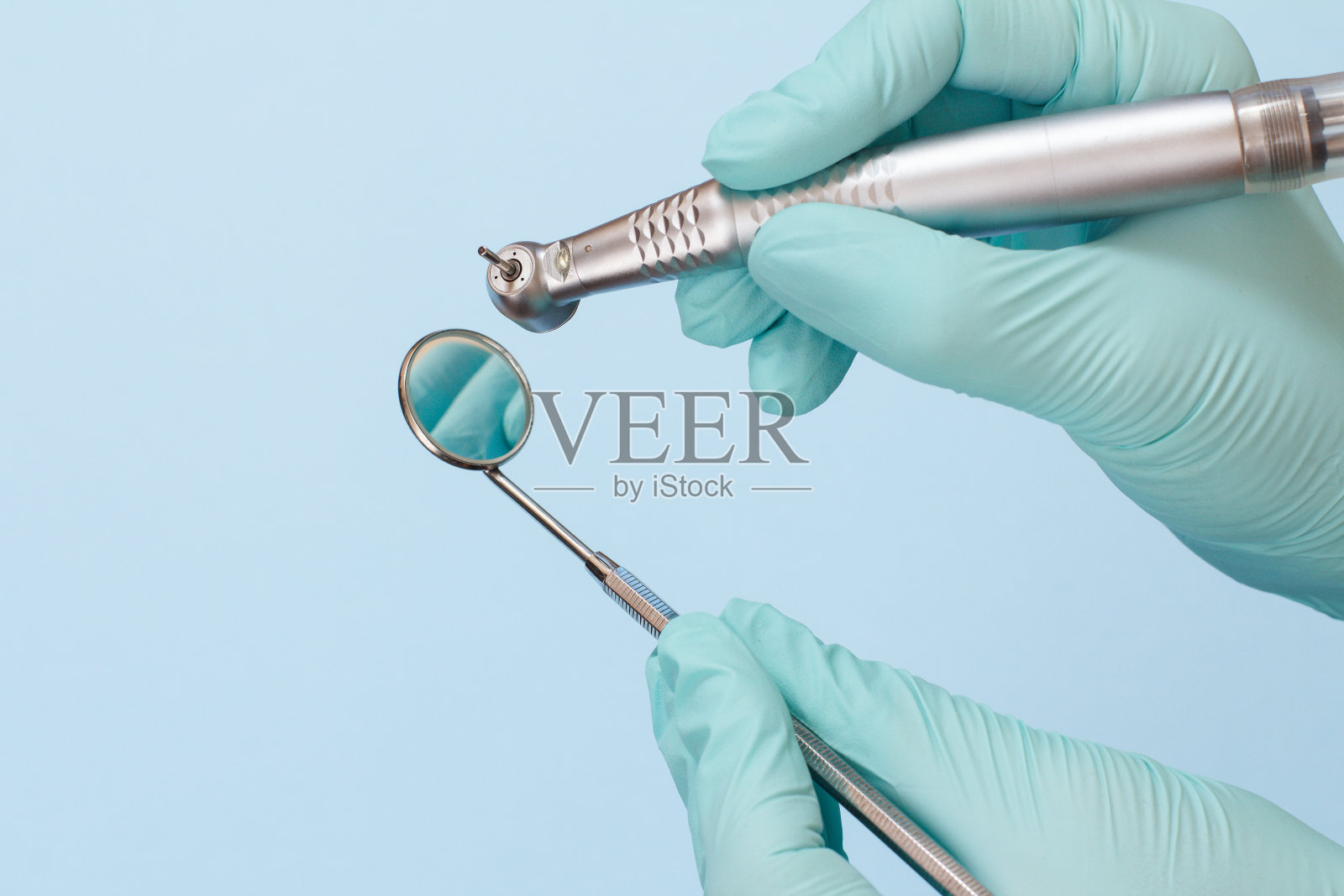 牙医的手戴着手套，戴着牙科电话和口镜。照片摄影图片