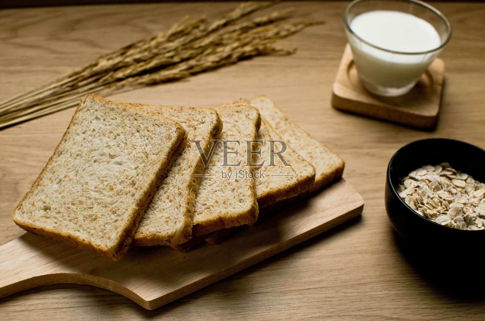 全麦面包片放在木板上，配上一杯牛奶和配料照片摄影图片