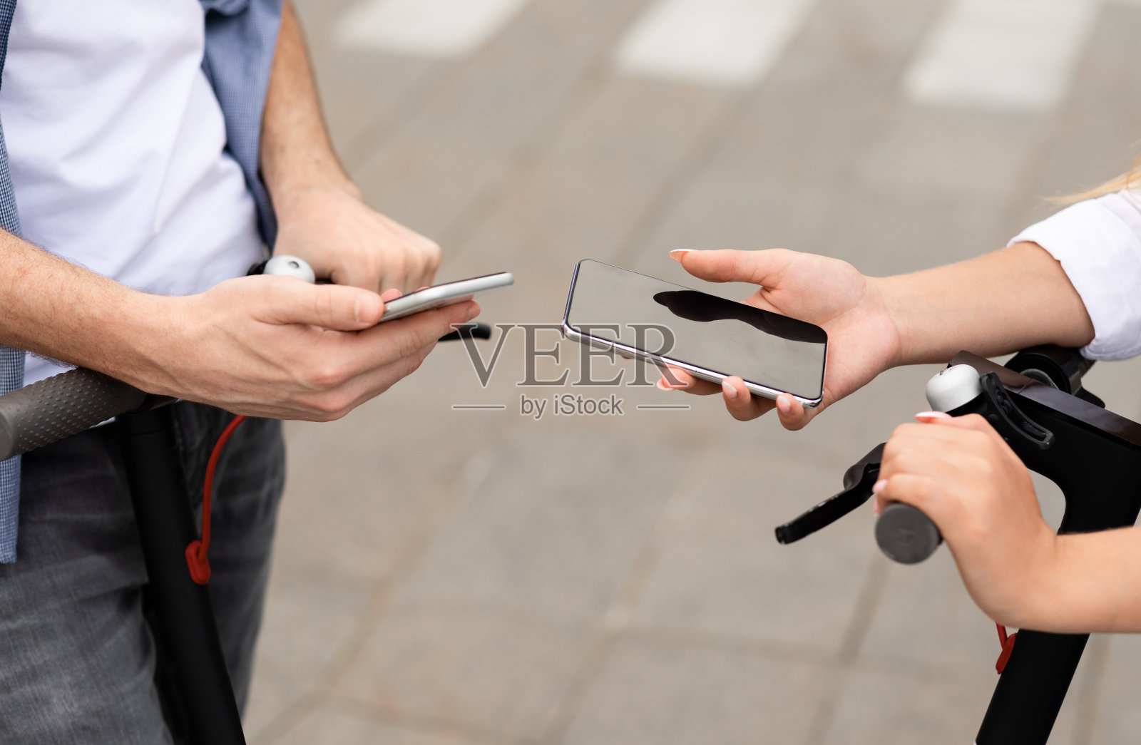 朋友们骑着电动滑板车，用着手机照片摄影图片