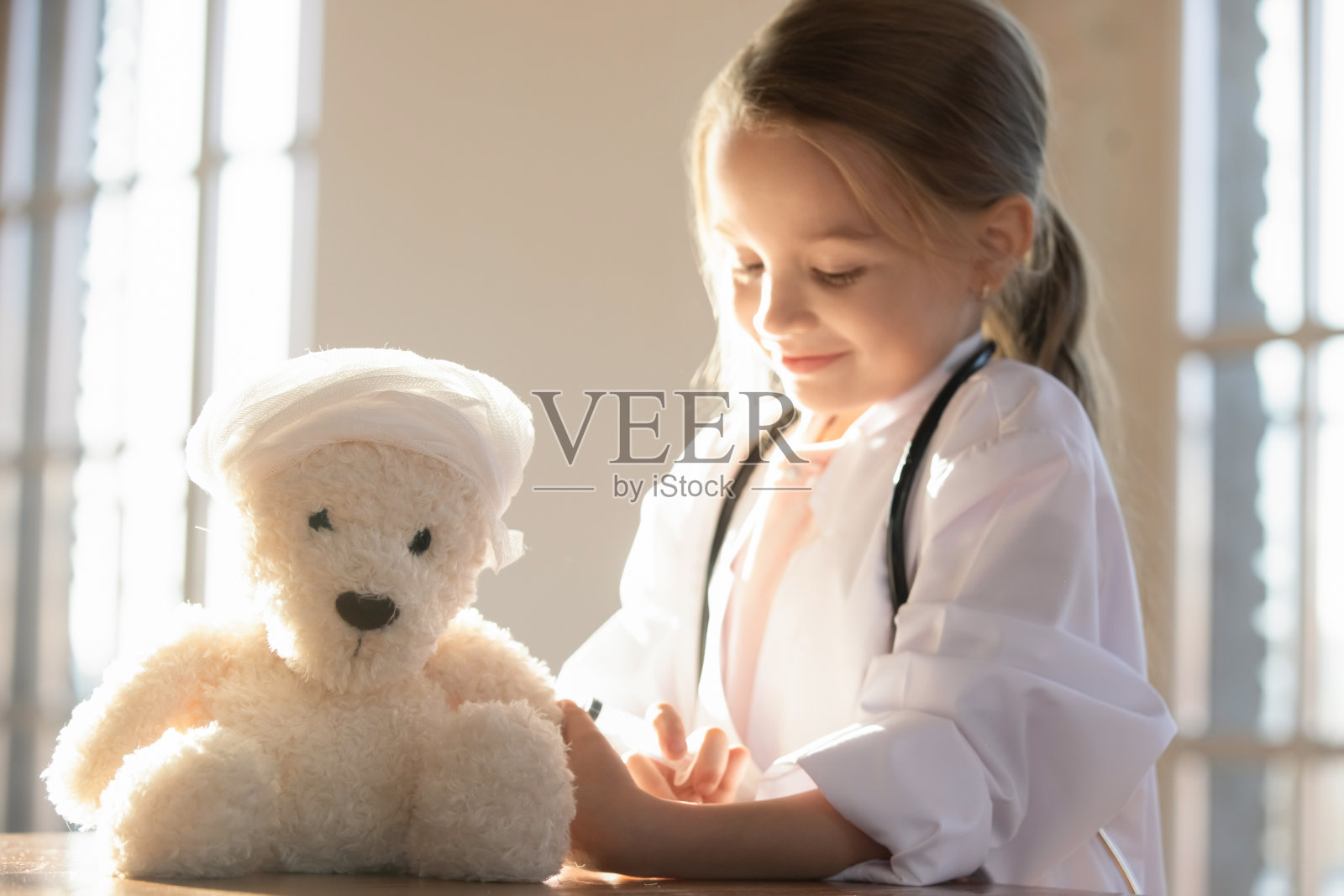 近距离可爱的小女孩假装医生接种玩具熊照片摄影图片