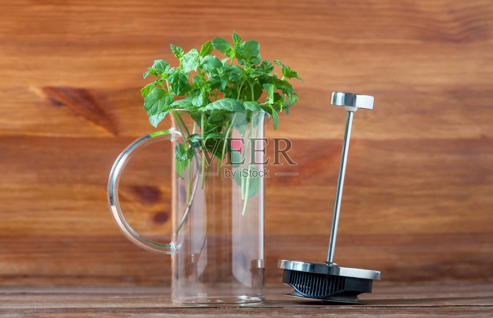 新鲜的绿色薄荷在一个玻璃压榨冲泡茶近距离在一个木材背景照片摄影图片