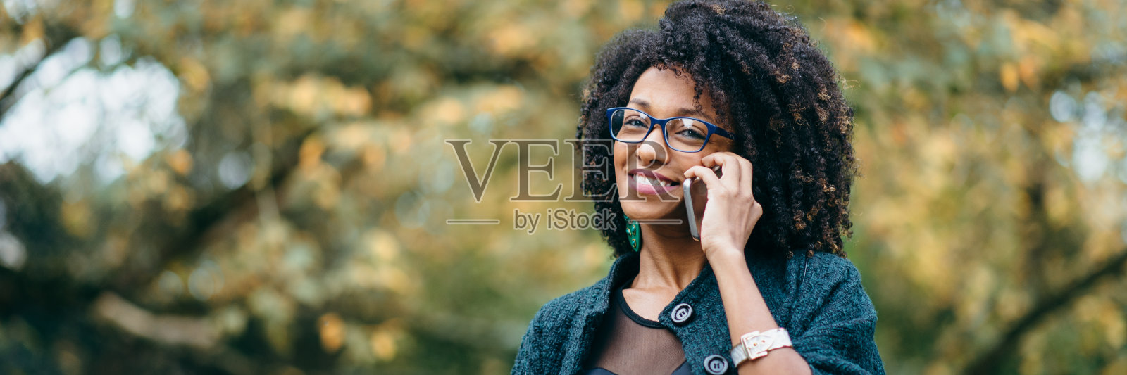 秋天里，一个快乐的黑人女人在打电话照片摄影图片